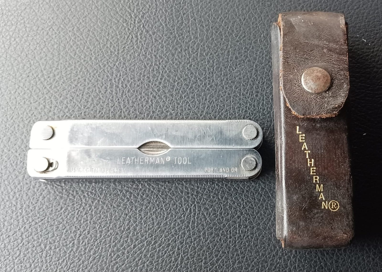 Original Leatherman Tool closed next to a brown leather Leatherman holster
